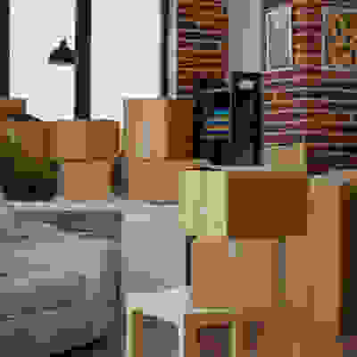 Living room with moving boxes and furniture wrapped in plastic, brick wall background.